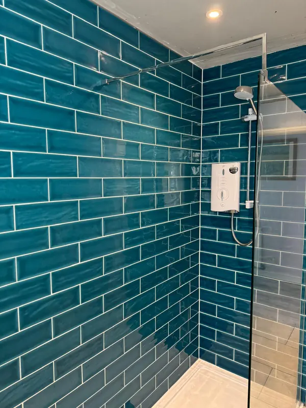 Walk-in shower with teal metro tiles and glass screen