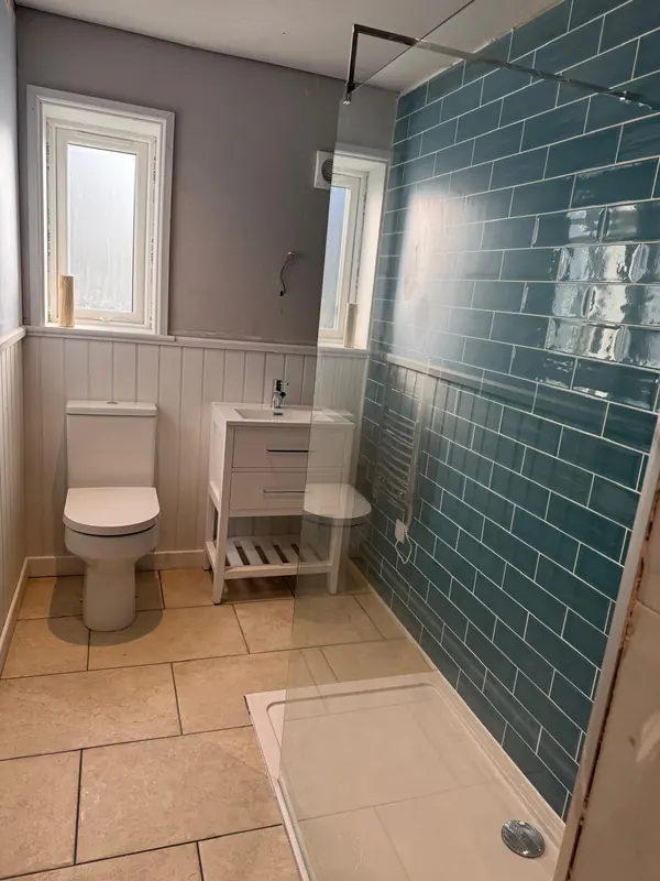 Bathroom with teal metro tiles, walk-in shower, white panelling and vanity unit
