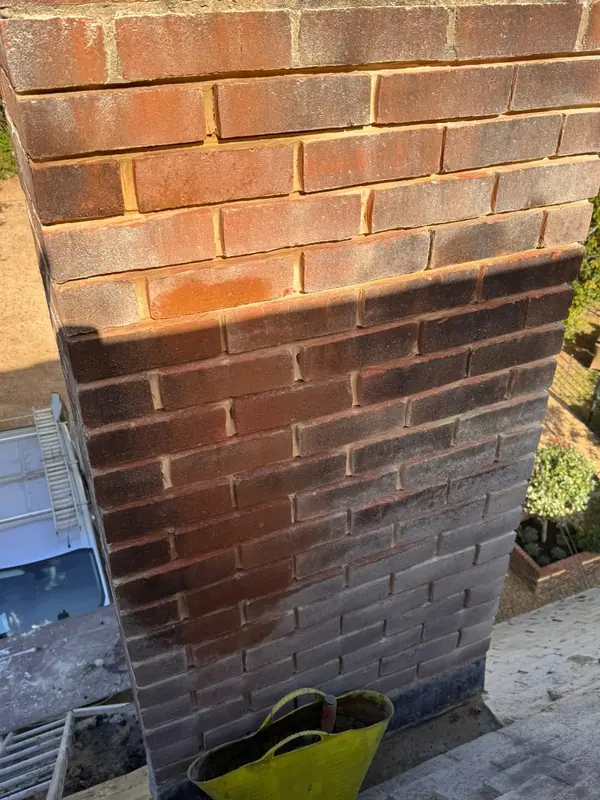 Back of a brick chimney part way through repointing