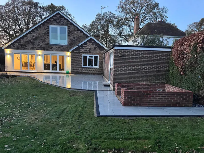 Back of a chalet bungalow with a new porcelain patio, brick raised bed and outdoor lights