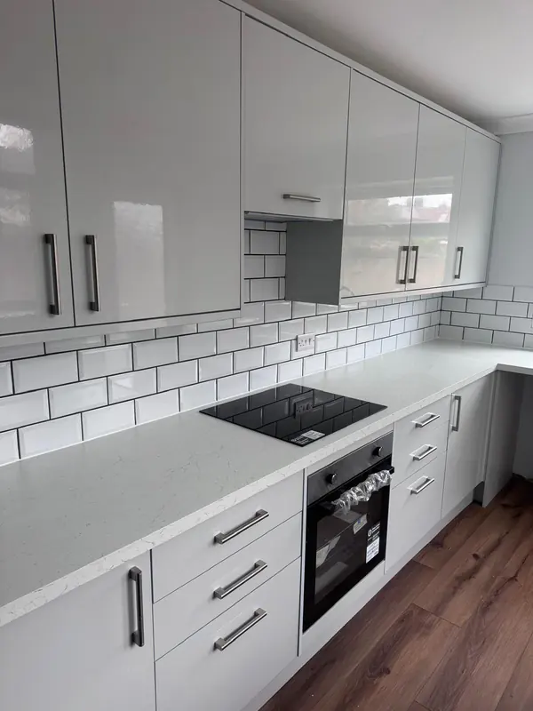 Light grey gloss kitchen units with an oven and metro tiles